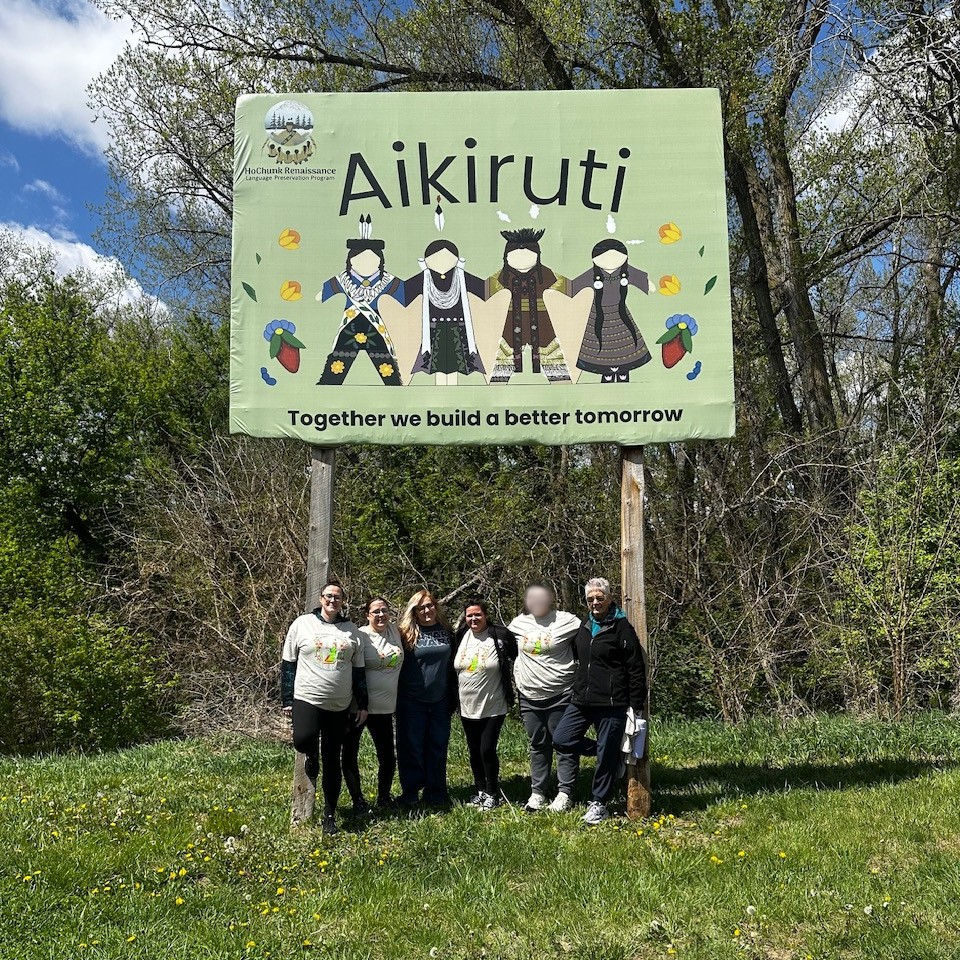 Seven women standing on the grass in front of a green Aikiruti sign