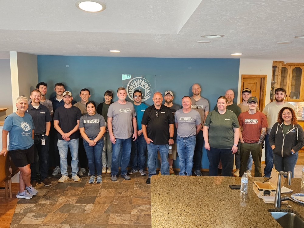 A work crew posing in the Talitha Koum kitchen, many wearing matching Interstates shirts